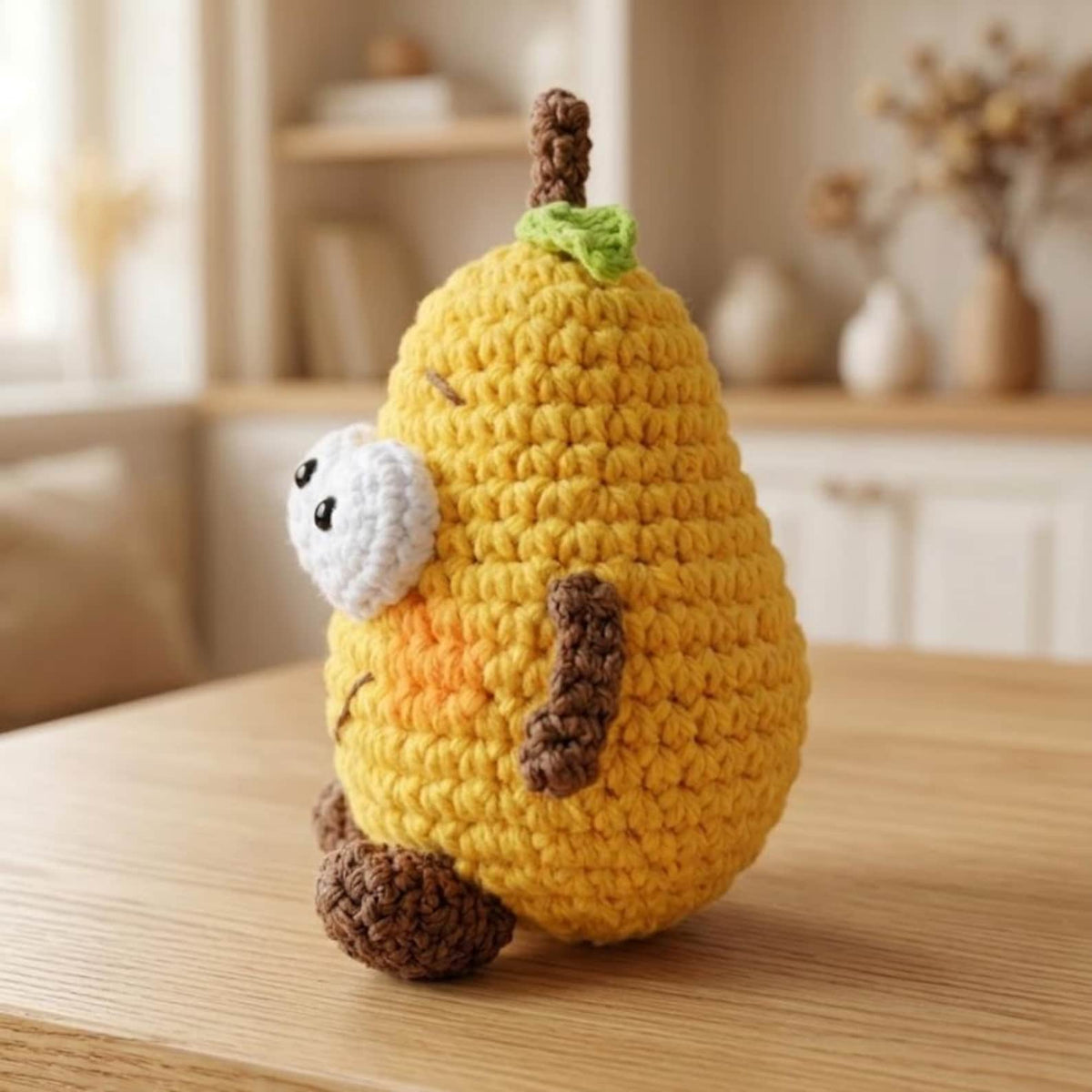 Handmade crochet pear amigurumi with googly eyes arms and legs side view