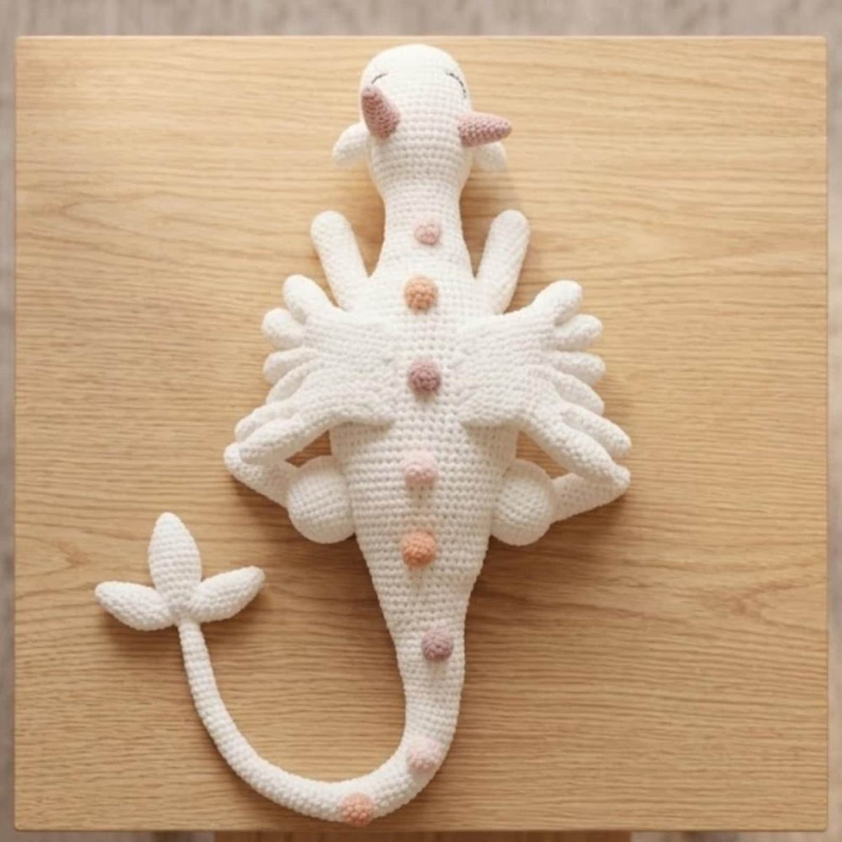 Giant white crochet unicorn dragon lying flat showing full wing detail top view